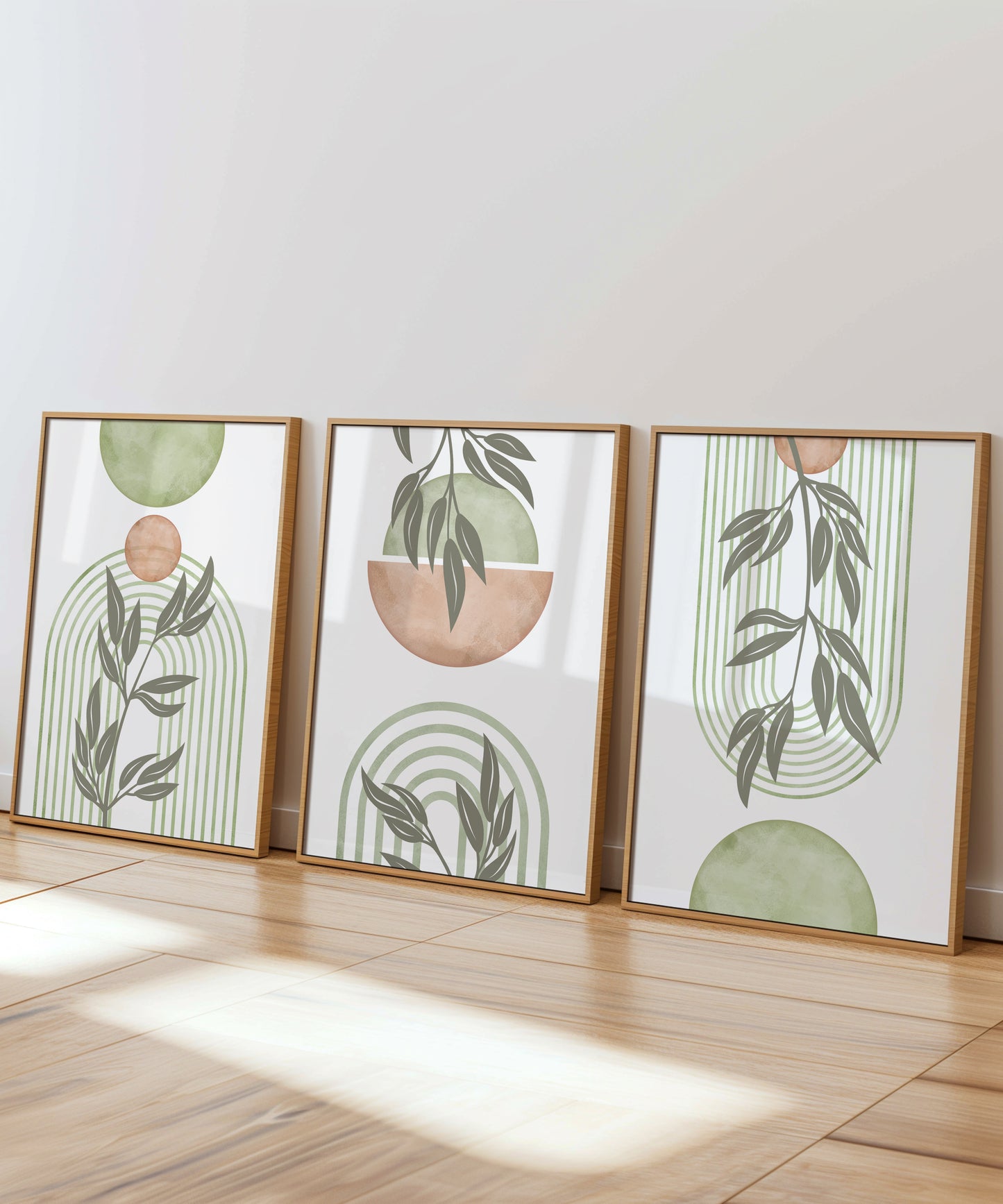 A stunning set of 3 Boho art prints showing circles and lines forming an arc in soft pink and sage green colours with botanical leaf silhouettes.