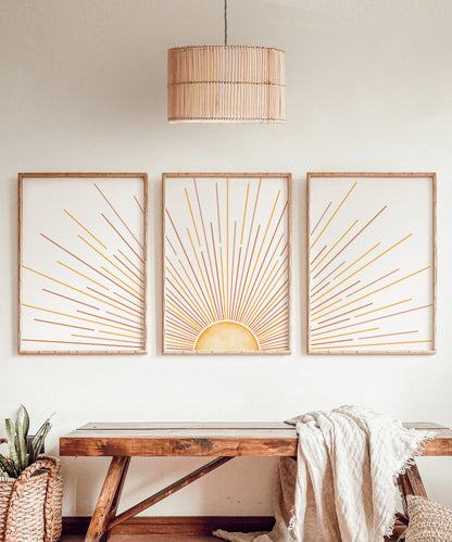 A vibrant set of 3 prints illustrating a sunrise in the centre with beaming rays of sunlight in orange and yellow streaks across the pages set on a white background.
