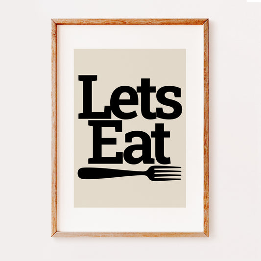 A typography kitchen print saying 'Lets Eat' in a black slab serif font with a fork silhouette underneath.
Set on a beige background.