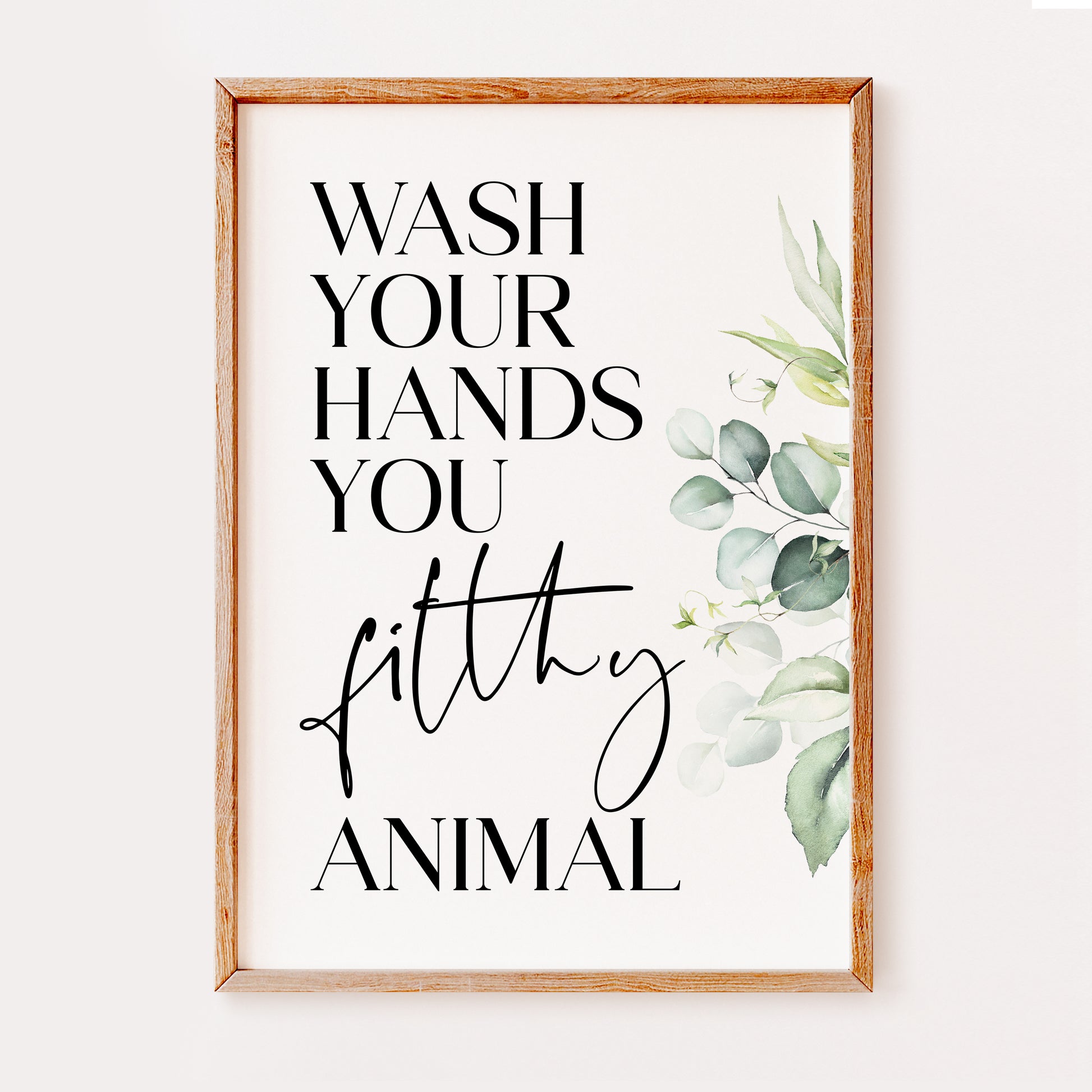 A humorous bathroom quote print saying 'Wash your hands you filthy animal', written in a stylish black font and with a eucalyptus floral design which makes this a great addition to add to your bathroom or washroom spaces.