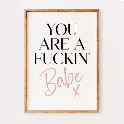 A fiery typography bedroom print with the words 'You are a fuckin' in a bold black font and 'Babe x' written in a stylish pink font set on a white background.